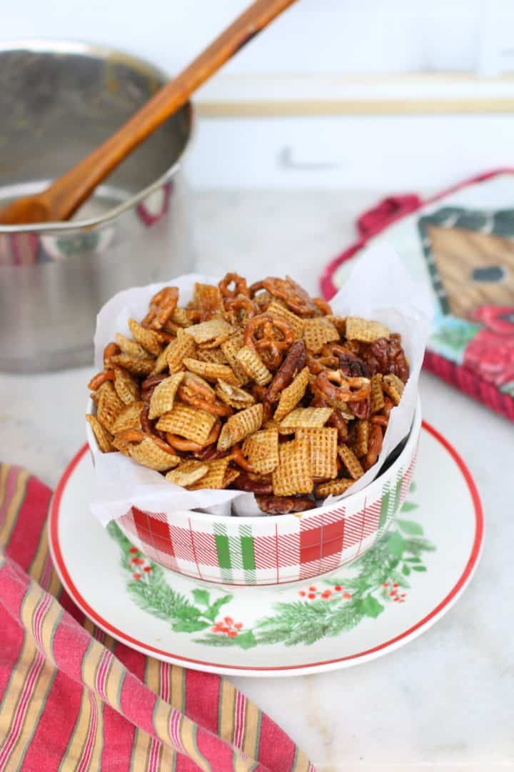 Bowl filled with praline crunch snack mix made with Chex cereal, mini pretzels, and pecans.